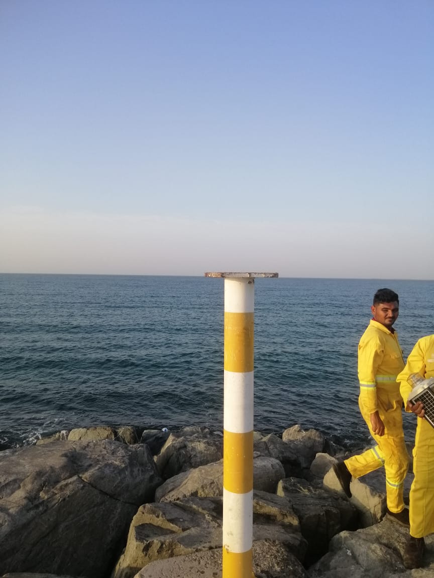 Technicians working on a navigation marker at the shoreline